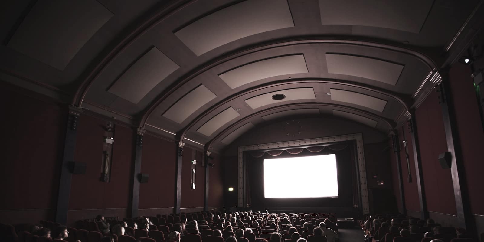 Sala de cine a oscuras con la pantalla encendida frente a las butacas