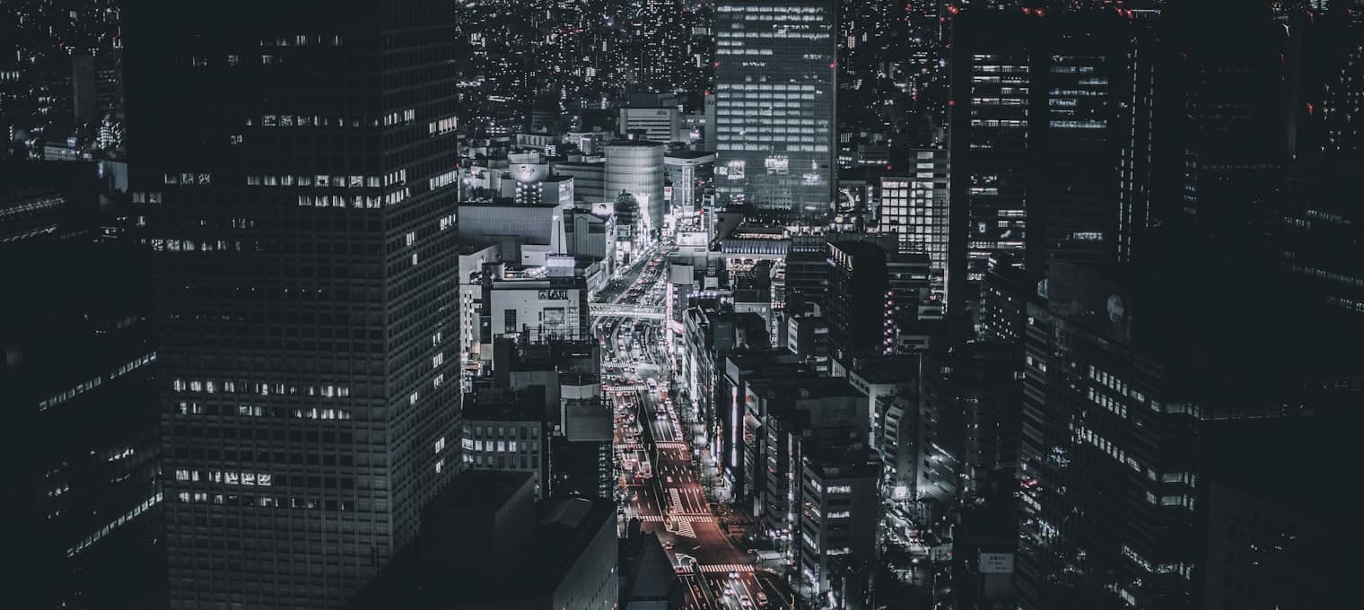 Vista aérea nocturna de una ciudad con las avenidas encendidas entre bloques oscuros